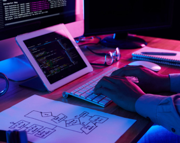 person working on 2 screens, typing on keyboard